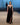 A model wearing a black, V-neckline, thin strap, sequin-embellished long dress with a front slit and a train on a runway.